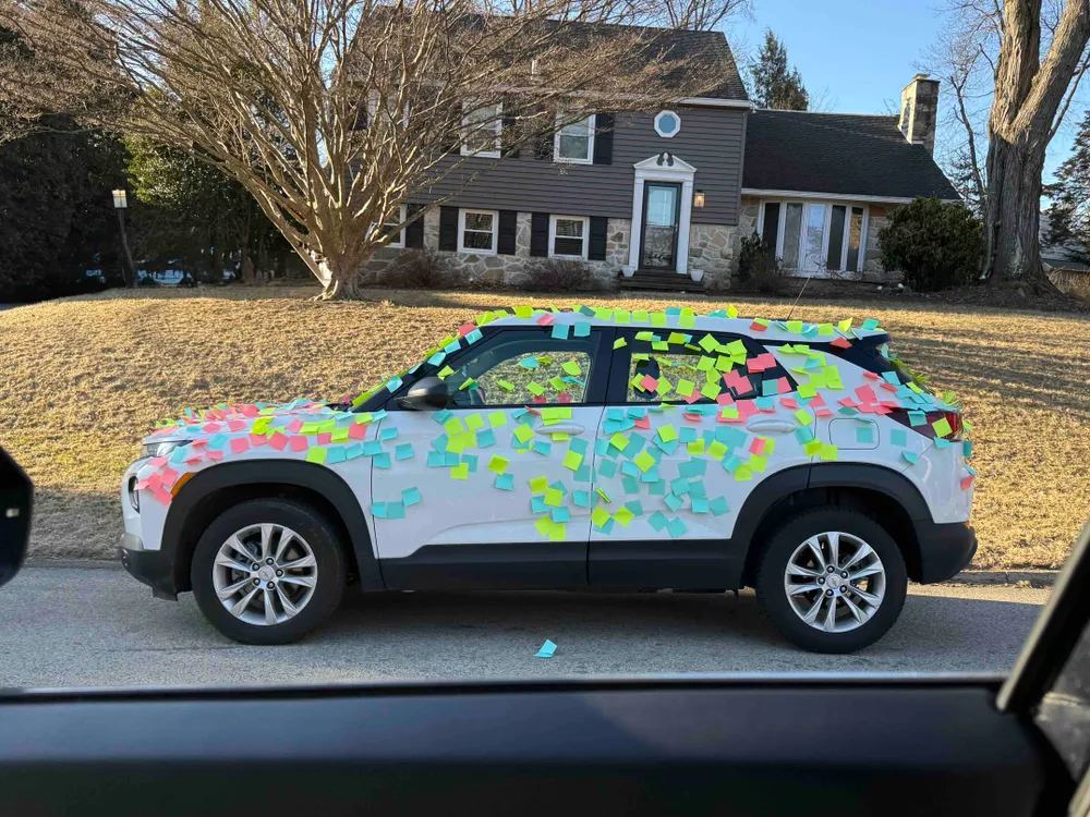 A white car covered with blank sticky notes.
